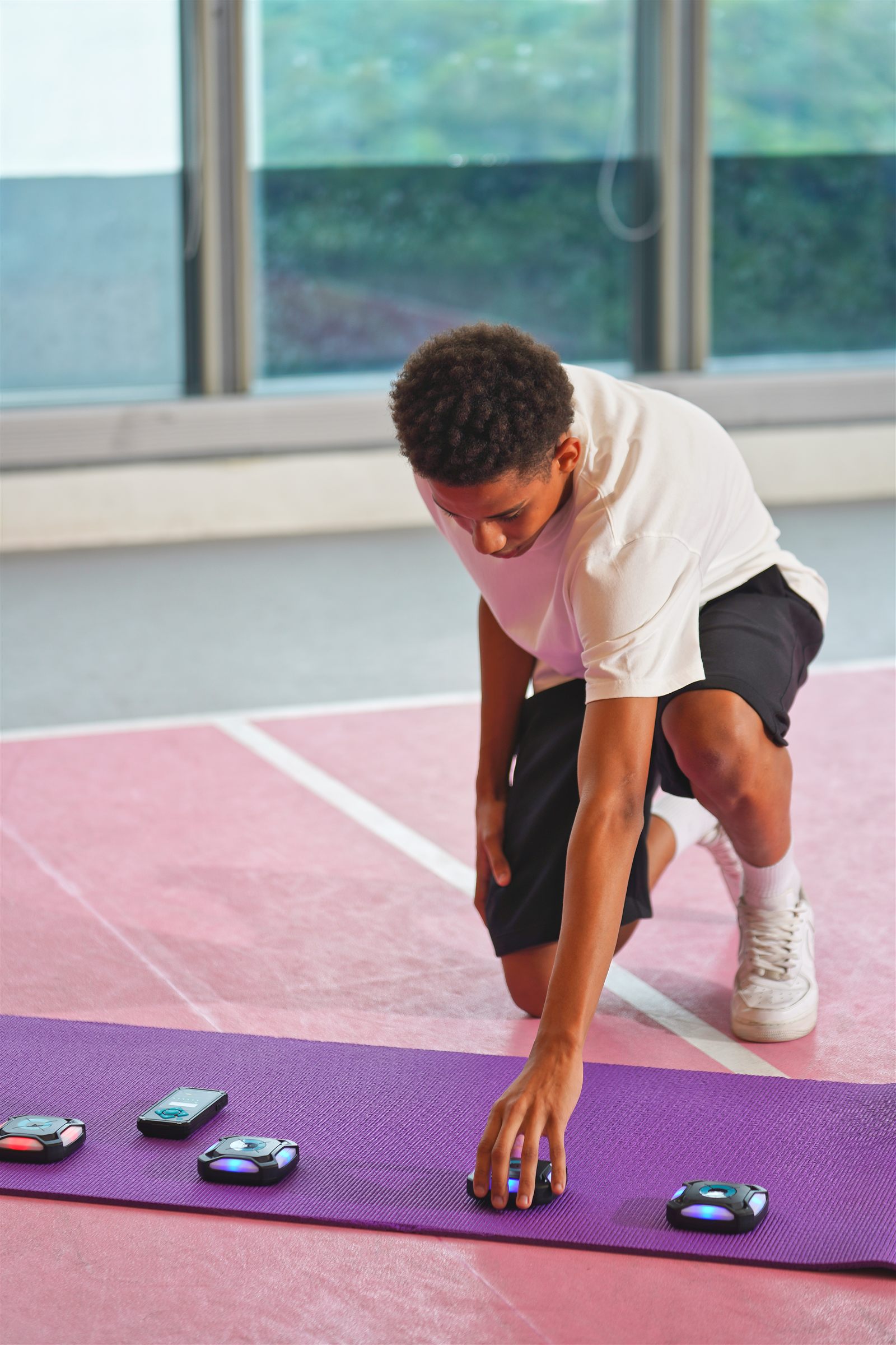Athlete reaching down mid-sprint to tap a glowing target, demonstrating a reactive sprint drill